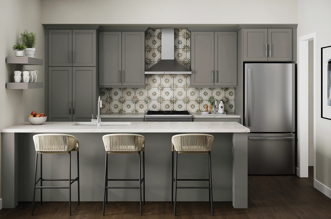 Medium-grey shaker range wall with a stainless chimney hood between tall cabinets, patterned tile behind the range and a peninsula with three woven stools