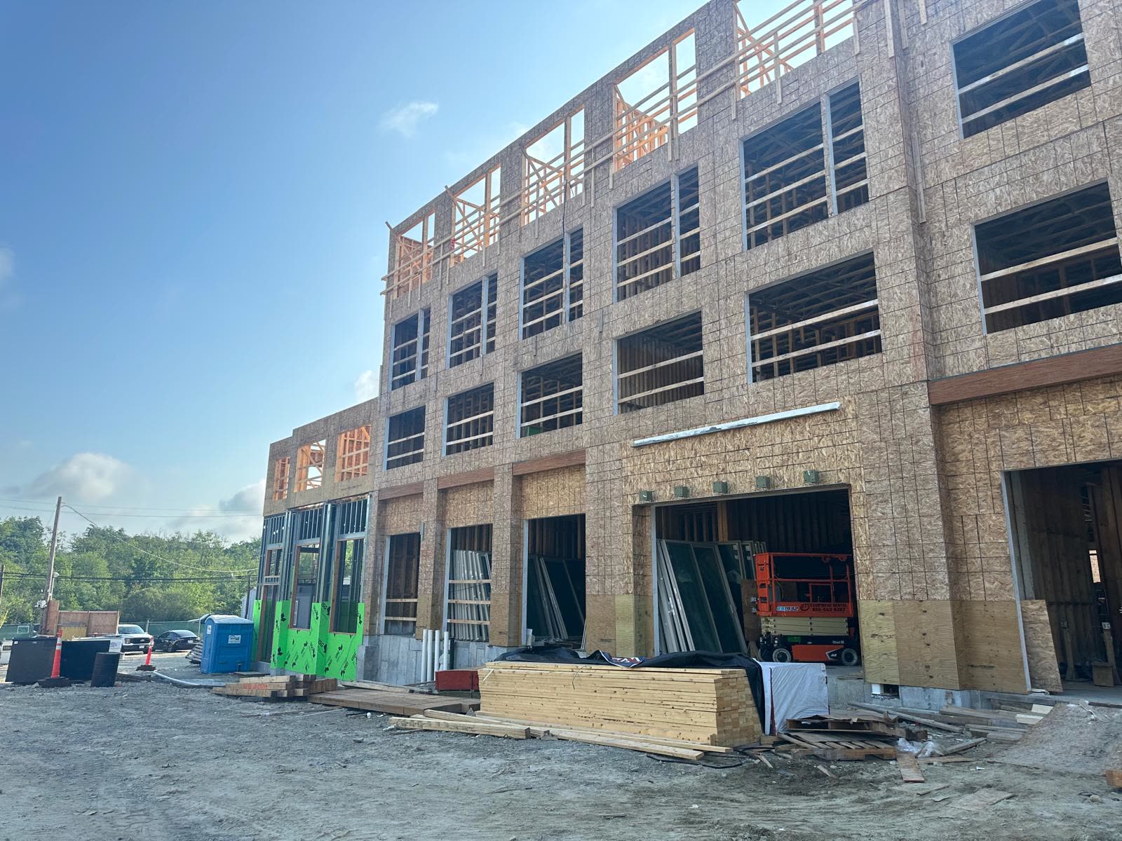 Framed building with open garage bays and a lumber package staged in front