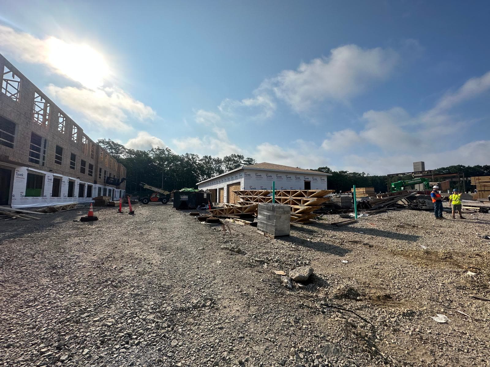 Floor trusses stacked at a jobsite in front of a wrapped building