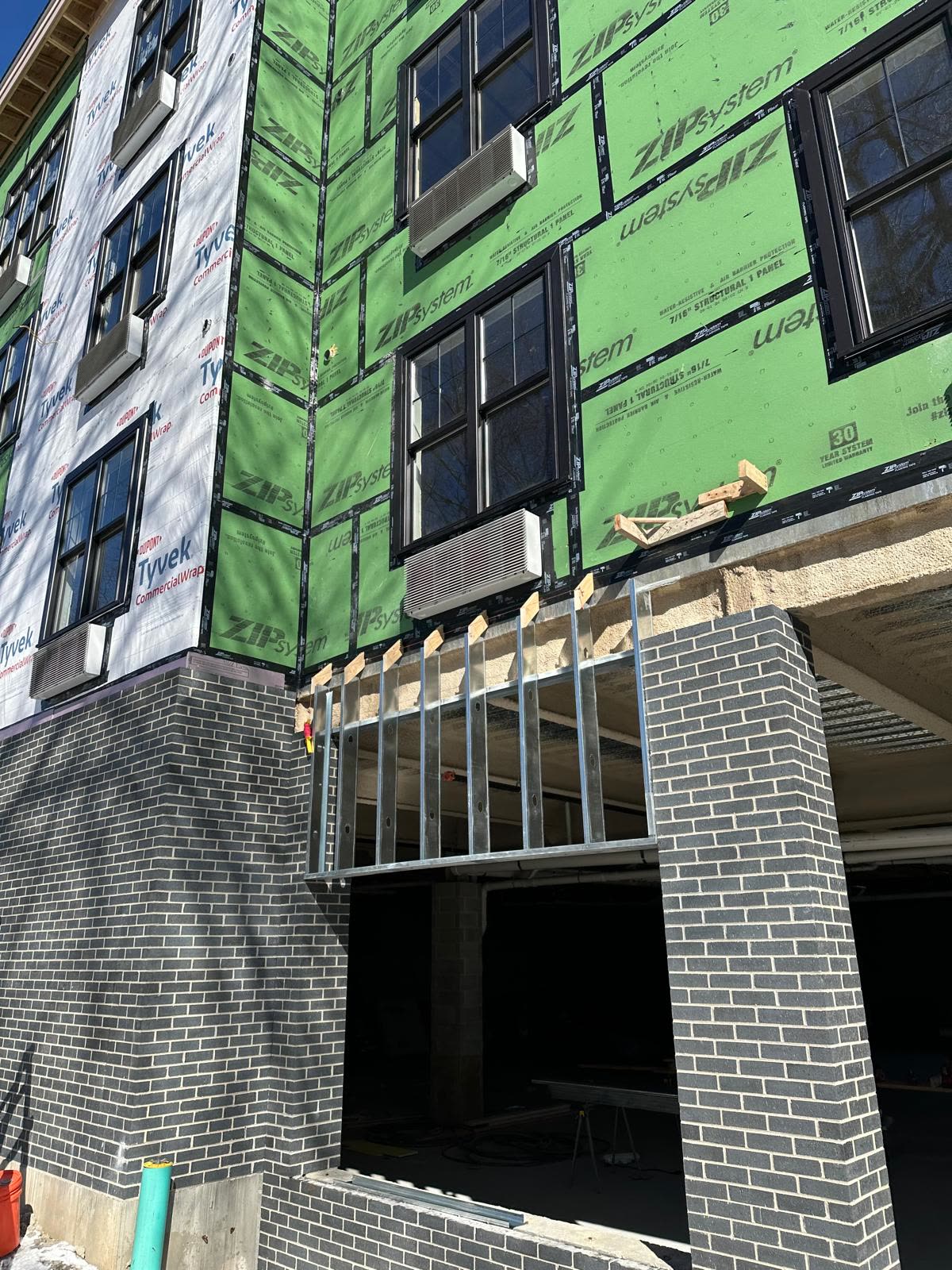 Corner of a podium building with housewrap and sheathing under a cloudy sky